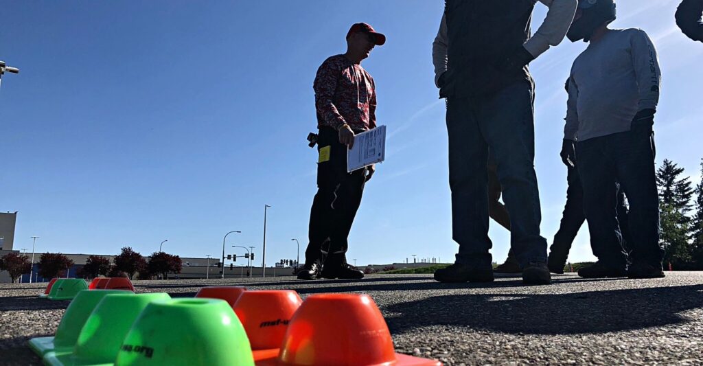 motorcycle students and instructors standing around some cones