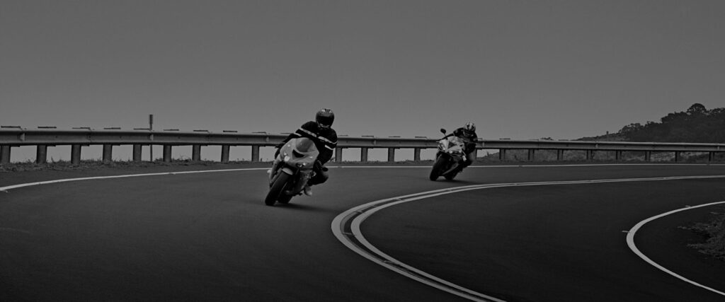 two motorcycle riders going around a corner after getting their endorsement