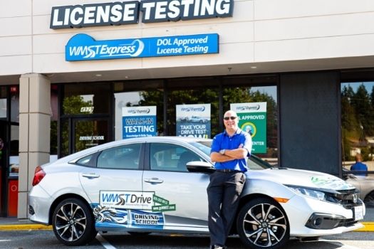 man wearing blue shirt leaning on driver license testing car in Everett